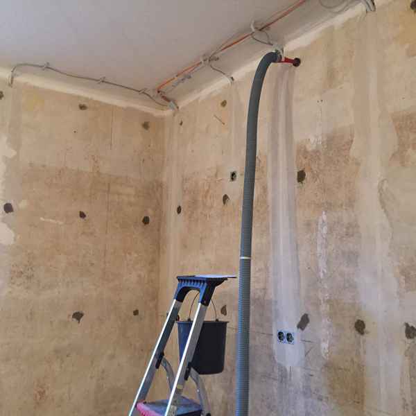 Durch mehrere Bohrungen wird die Steinwolle in den Hohlraum der Außenwand eingebracht.