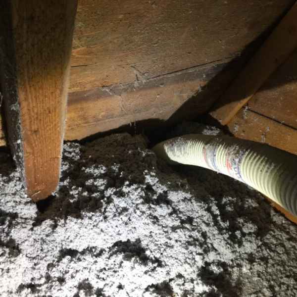 Einfamilienhaus mit ungedämmter Dachschräge während der Dämmstoff eingeblasen wird.